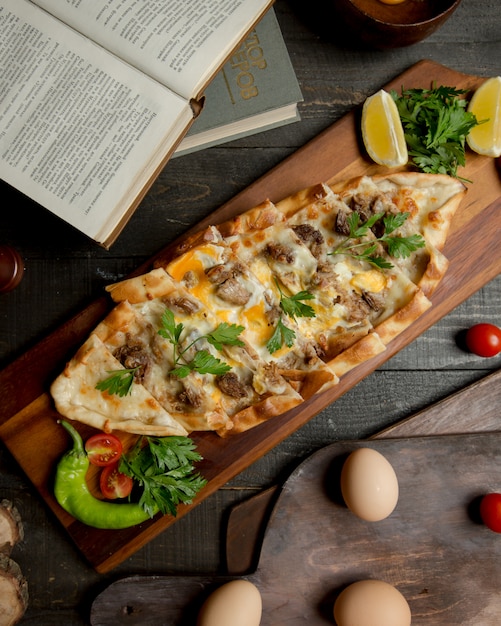 Pizza turque pide avec des aliments mélangés et des herbes.