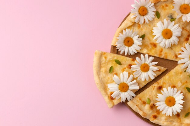 Pizza vue de dessus avec des fleurs sur fond rose