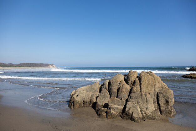 Plage entourée par la mer et les rochers sous la lumière du soleil et un ciel bleu au Mexique