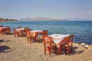 Photo gratuite plage grecque avec tables et chaises bleues traditionnelles