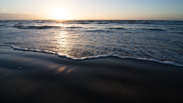 Plage de l'océan avec des vagues de lumière sur le sable