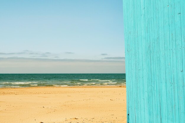 Plage de sable de la côte de la mer l'idée de vacances d'été en mer il est temps de partir en vacances Mur en bois de la maison de plage dans un espace publicitaire de couleur turquoise