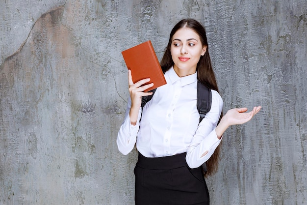 Plan d'une belle adolescente avec un sac à dos tenant un livre. Photo de haute qualité