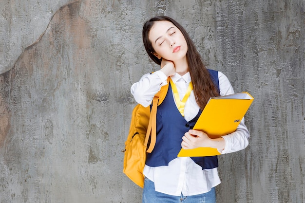 Plan d'une belle fille avec un dossier jaune debout. Photo de haute qualité