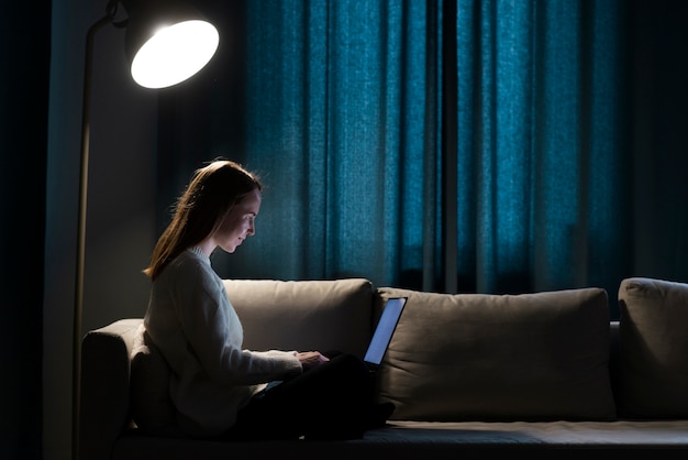 Plan complet d'une femme travaillant sur un canapé