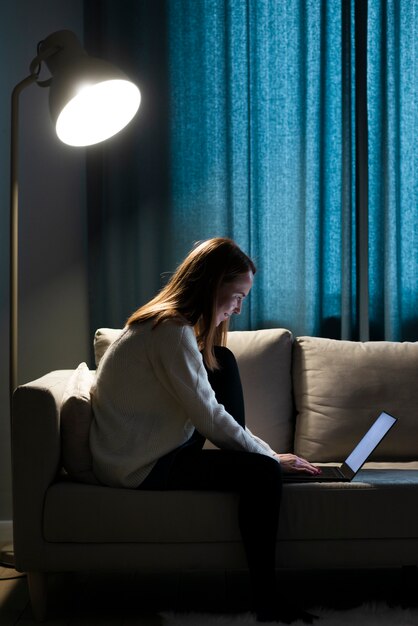 Plan complet d'une femme travaillant sur un canapé