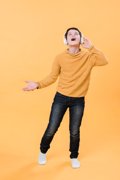 Photo gratuite plan complet d'un garçon écoutant de la musique avec des écouteurs