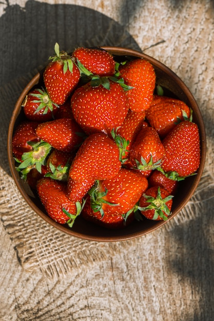 Photo gratuite plan descendant d'un bol d'argile rempli de fraises rouges mûres.