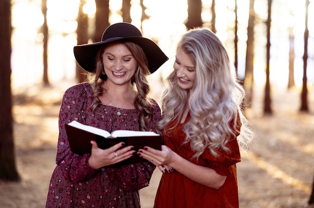 Plan de deux jeunes femmes posant avec un livre dans la forêt, humeur d'automne