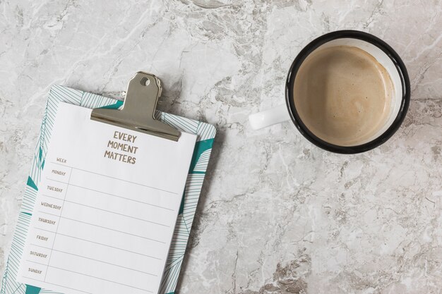 Plan hebdomadaire sur le presse-papiers et tasse de café sur le fond de marbre