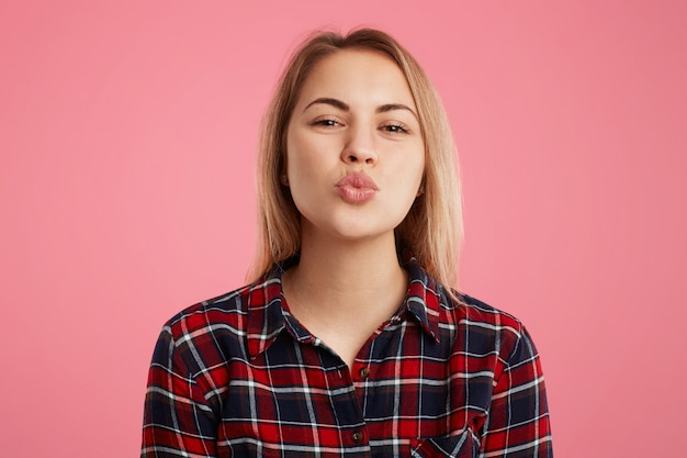 Plan horizontal d'une belle femme aux lèvres arrondies, va embrasser son petit ami, exprime un grand amour et de bons sentiments