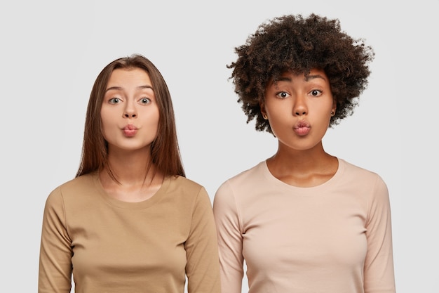 Plan horizontal de filles multiraciales font des baisers avec des lèvres, flirtent avec de beaux mecs