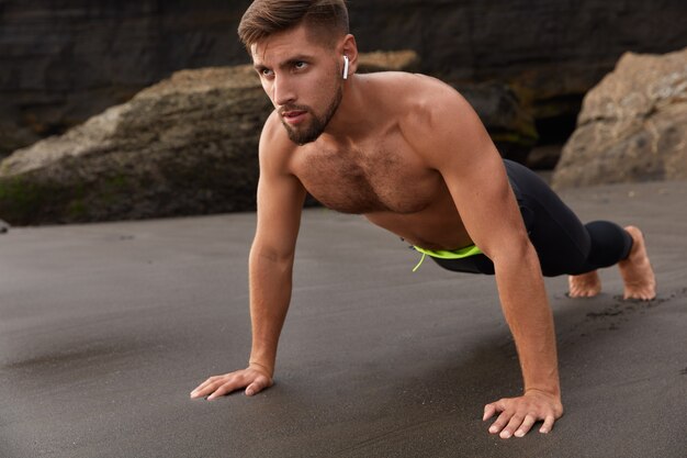 Plan horizontal d'un jeune sportif musclé ou d'un athlète fait la position de la planche, profite de l'air marin frais