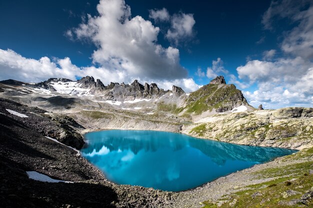 Plan horizontal d'un plan d'eau entouré de montagnes rocheuses sous le beau ciel nuageux