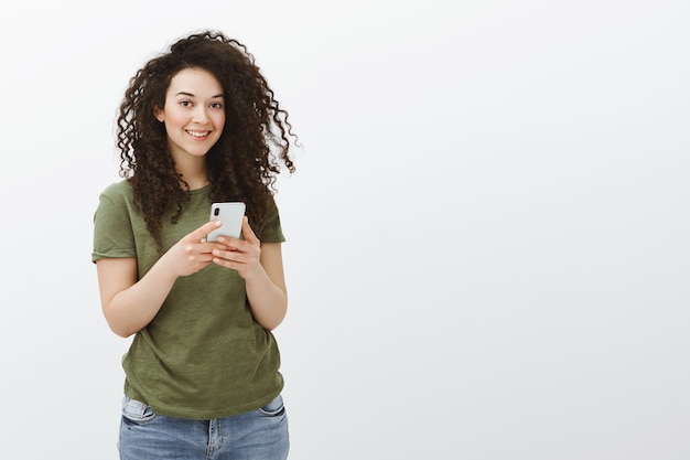 Plan intérieur d'une charmante employée aux cheveux bouclés séduisante en t-shirt décontracté