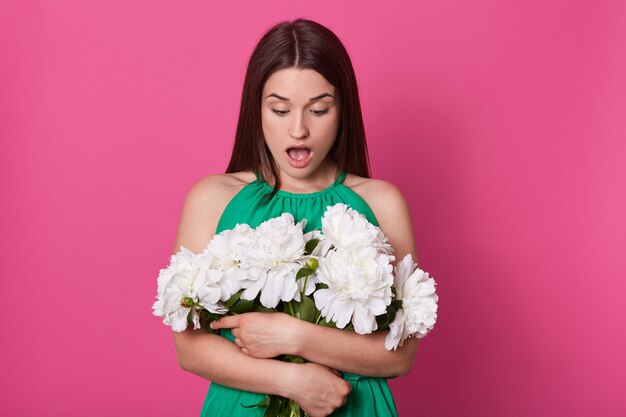 Plan intérieur de choqué impressionné jeune femme regardant le bouquet avec la bouche ouverte
