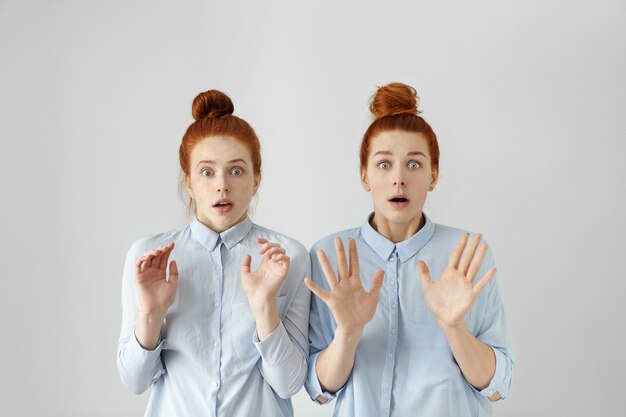 Plan à l'intérieur de deux jeunes femmes européennes aux yeux d'insectes terrifiés avec des nœuds de cheveux