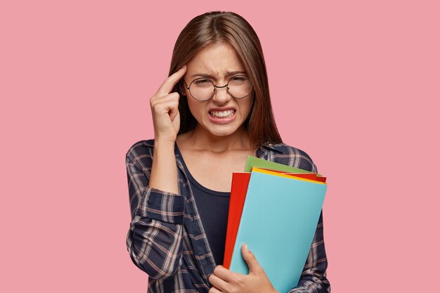 Plan intérieur d'une femme européenne stressante garde la main sur la tempe, souffre de maux de tête, serre les dents