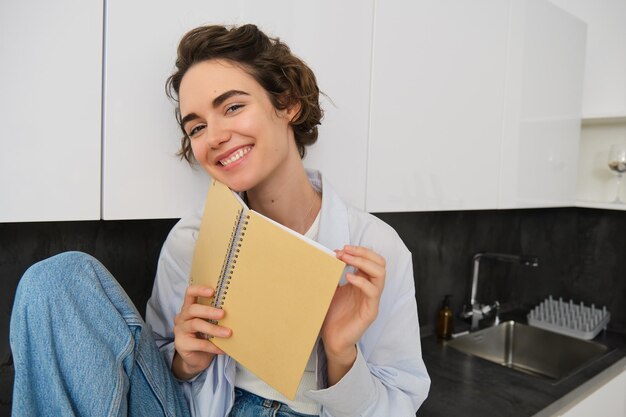 Plan intérieur d'une jeune femme se relaxant à la maison en lisant un journal étudiant confortablement en passant du temps à l'intérieur