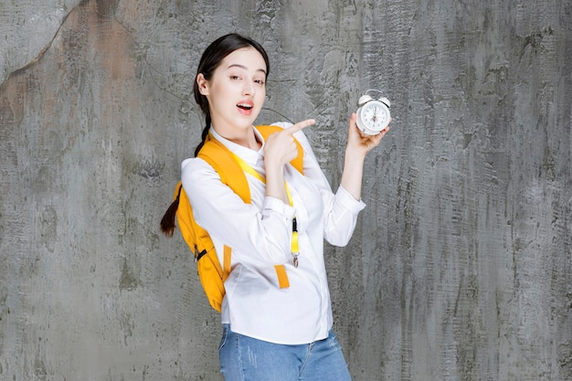 Plan d'un jeune étudiant avec un sac à dos indiquant l'heure sur l'horloge. Photo de haute qualité