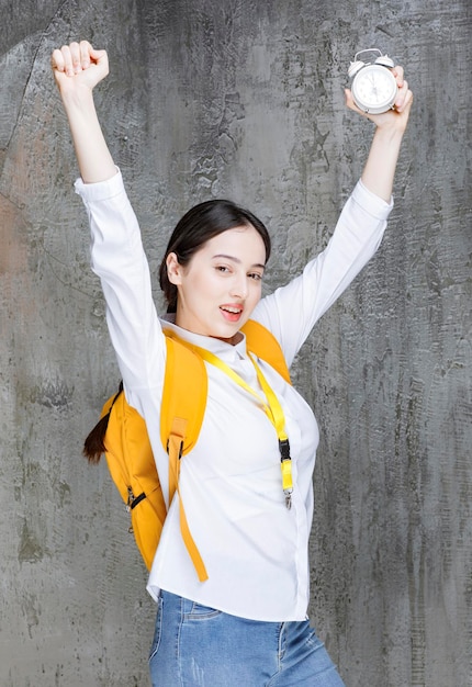 Photo gratuite plan d'un jeune étudiant avec un sac à dos indiquant l'heure sur l'horloge. photo de haute qualité