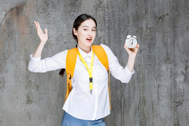 Plan d'un jeune étudiant avec un sac à dos indiquant l'heure sur l'horloge. Photo de haute qualité