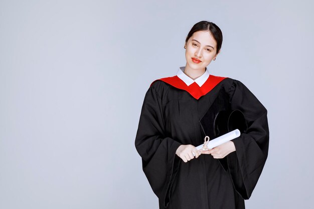 Plan d'un jeune étudiant en toge et diplôme posant devant la caméra. photo de haute qualité