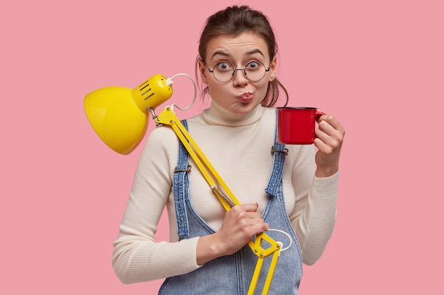 Plan d'un joli jeune porte-monnaie, porte une tasse avec du thé et une lampe de bureau jaune, prêt pour l'étude