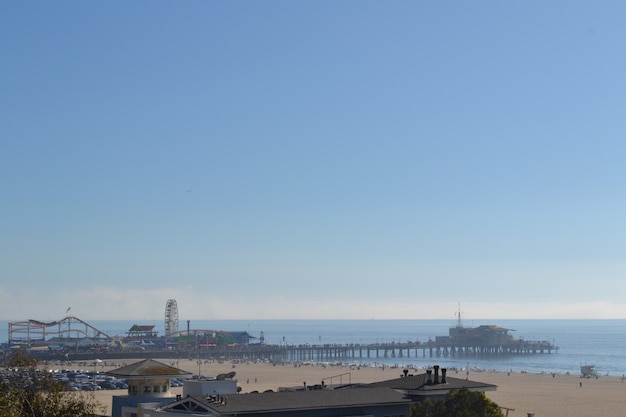 Photo gratuite plan large et lointain d'un parc d'attractions sur un quai au bord de la mer sous un ciel bleu clair