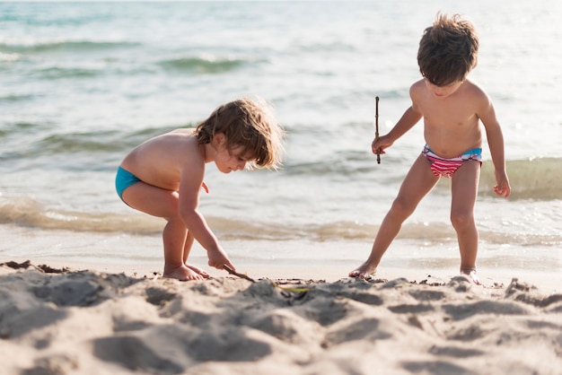 Plan long d&#39;enfants jouant à la plage