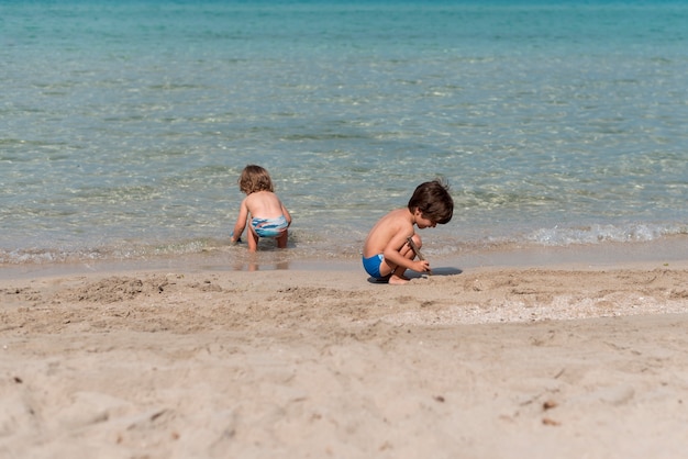 Plan long d&#39;enfants jouant à la plage