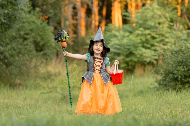 Plan long de fille avec costume d'halloween de sorcière dans la nature