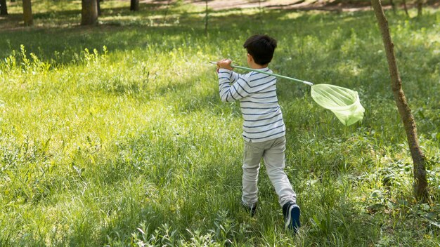 Plan long d'un garçon essayant d'attraper des papillons