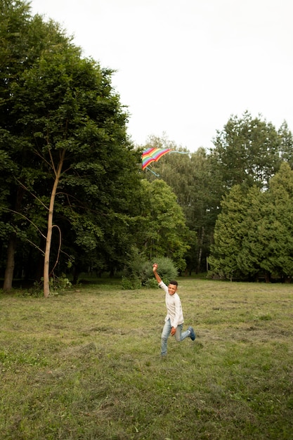 Photo gratuite plan long d'un garçon heureux s'amusant avec un cerf-volant