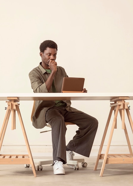 Plan long d'une personne assise et travaillant sur un ordinateur portable