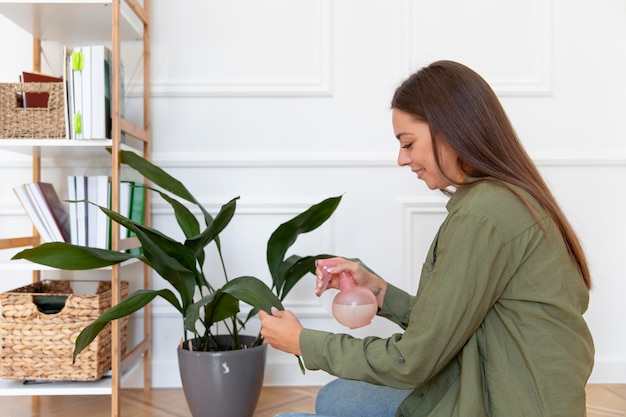 Photo gratuite plan moyen femme arrosant la feuille