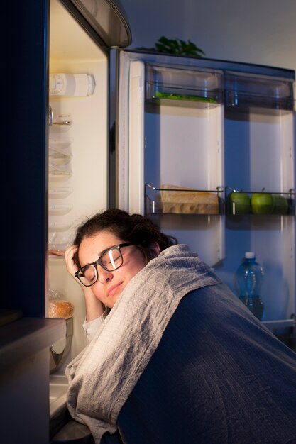 Plan moyen femme vérifiant le réfrigérateur pour une collation