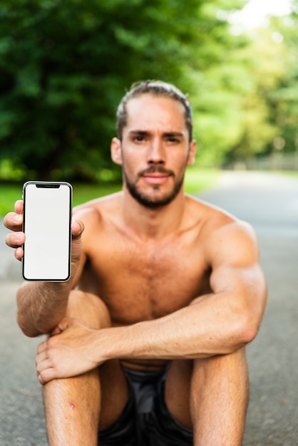 Photo gratuite plan moyen d'un homme tenant une maquette de téléphone
