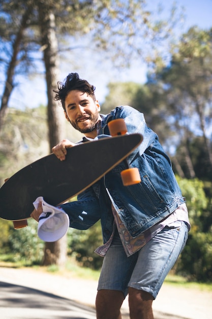 Plan moyen d'un homme tenant une planche à roulettes