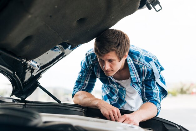 Plan moyen d'un homme travaillant sur un moteur