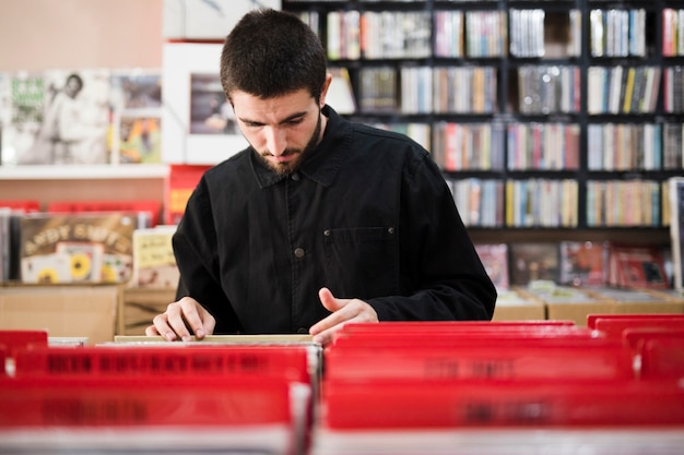 Plan moyen d&#39;un jeune homme à la recherche de vinyles en magasin