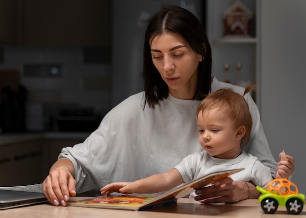 Photo gratuite plan moyen mère et bébé avec livre