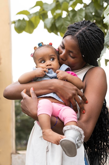 Photo gratuite plan moyen mère embrassant bébé fille