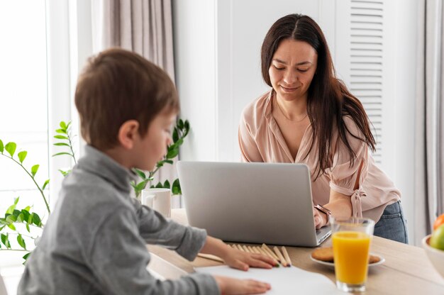 Plan moyen mère travaillant avec un ordinateur portable