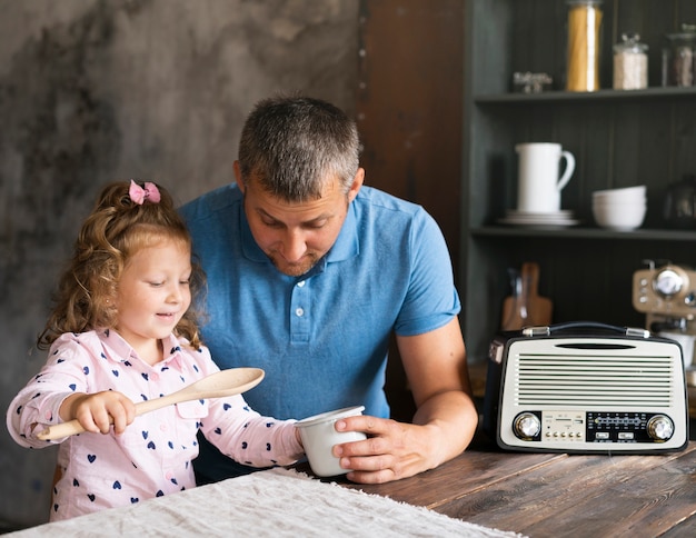 Photo gratuite plan moyen père assis avec sa fille dans la cuisine