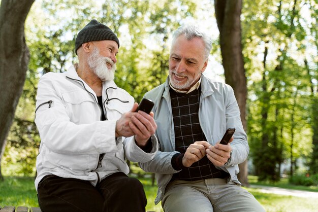 Plan moyen de vieillards souriants avec des smartphones