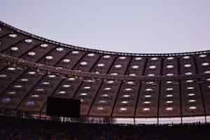 Photo gratuite plan partiel d'un stade affichant le toit, un grand écran, des rangées de sièges et des chaises