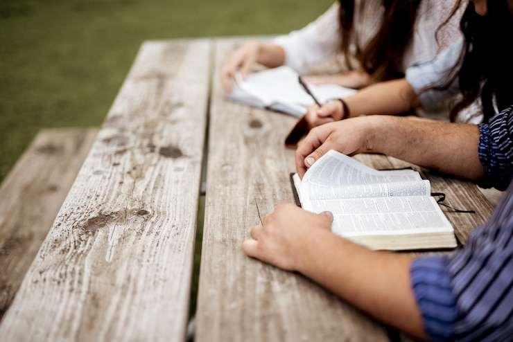 Photo gratuit plan de personnes assises les unes à côté des autres et lisant la bible