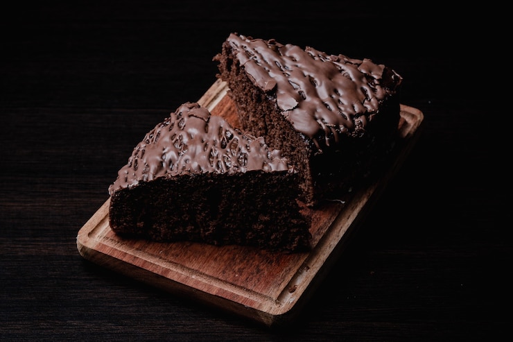 Photo gratuit plan rapproché de deux morceaux de gâteau au chocolat savoureux sur une planche en bois