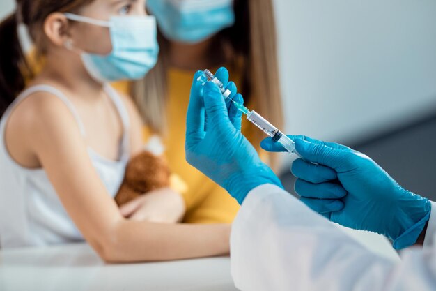 Plan rapproché du docteur préparant une seringue pour la vaccination de l'enfant